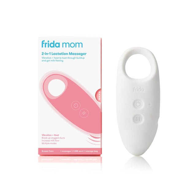 Package of the Frida Mom Lactation Massager placed next to a white massager standing up.  Package says, 2 in 1 lactation massager, vibration plus heat to bust through buildup and get milk flowing.